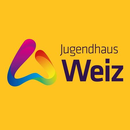 Das Logo des Jugendhaus Weiz zeigt einen stilisierten Buchstaben 'A' mit einem lebendigen Farbverlauf von Lila zu Grün auf einem leuchtend gelben Hintergrund. Darunter sind die Worte Jugendhaus Weiz in fetter, dunkler Blauschrift zu sehen.