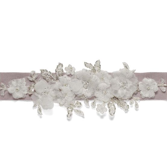 Ein Gürtel mit einem rosa Band und weißen Spitzenblumen mit Silberkristallen.