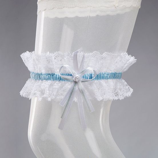 Ein weißer und hellblauer Spitzenhalter mit einer Schleife und Perle, befestigt an einer weißen Strumpfhose, die auf einem grauen Hintergrund ausgestellt ist.