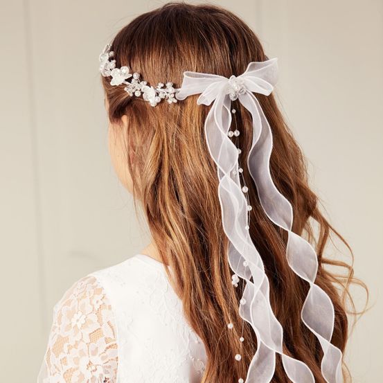 Eine Frau mit langen Haaren trägt eine weiße Blumenkopfband mit Perlenakzenten und einem passenden Band.