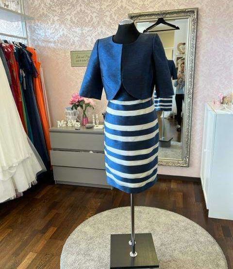 Ein marineblaues und weißes gestreiftes Kleid wird in einem Raum mit Spiegel, Holzboden und weißem Schrank ausgestellt.