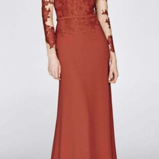 Eine Frau trägt ein langes kastanienbraunes Kleid mit Spitzenärmeln vor weißem Hintergrund. Das Kleid hat komplizierte Spitzenmuster an den Ärmeln.