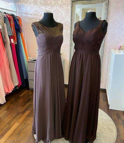 Zwei braune Brautjungfernkleider auf Mannequins in einem Bekleidungsgeschäft. Ein Kleiderständer dahinter und ein Spiegel an der Wand.