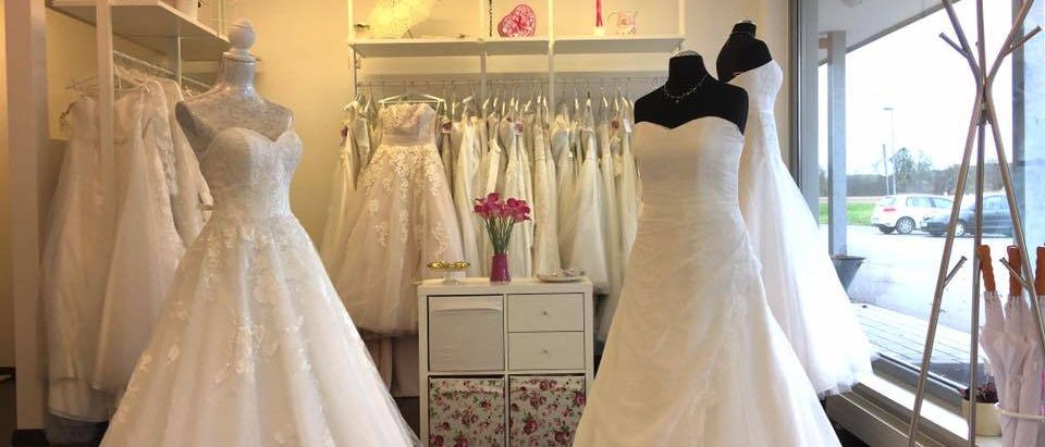 Ein Brautkleid-Geschäft zeigt verschiedene Hochzeitskleider auf Mannequins, mit dekorativen Elementen und Beleuchtung.