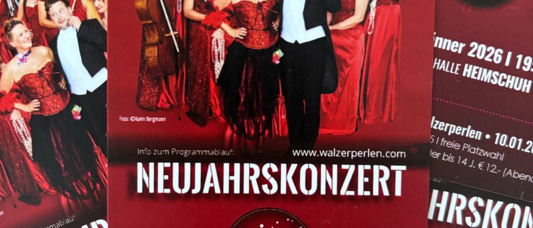 Ein rotes Plakat für ein Neujahrskonzert zeigt eine Gruppe von Frauen und einen Mann in formeller Kleidung. Der Text lautet 'Neujahrskonzert' und 'Samstag, 10. Januar 2026 | 19:30 Uhr'. Die Gruppe spielt verschiedene Instrumente.