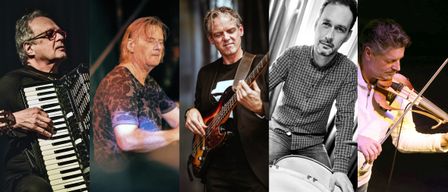 Drei Musiker posieren für ein Foto. Der linke hat rote Haare, der mittlere spielt Gitarre und der rechte sitzt mit einem Schlagzeug.