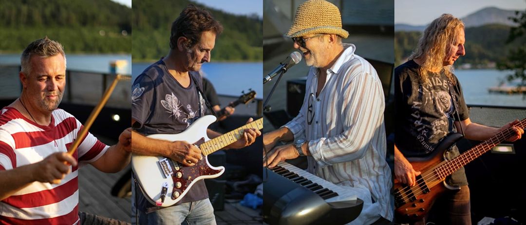 Zwei Männer treten auf der Bühne auf; einer spielt Gitarre, der andere singt in ein Mikrofon. Beide tragen lässige Kleidung, und ein See und Berge sind im Hintergrund.