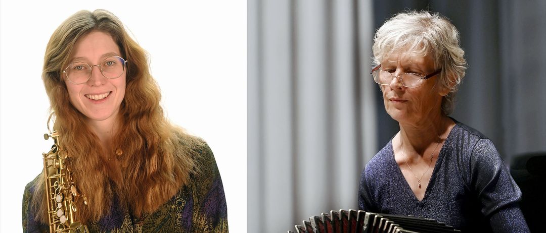 Eine Frau mit langen blonden Haaren in einem gemusterten Shirt und eine Frau mit Brille spielt ein Akkordeon.