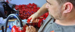 Ein Mann hält einen Feuerlöscher und untersucht ihn in einem Lager oder einer Lagerhalle.