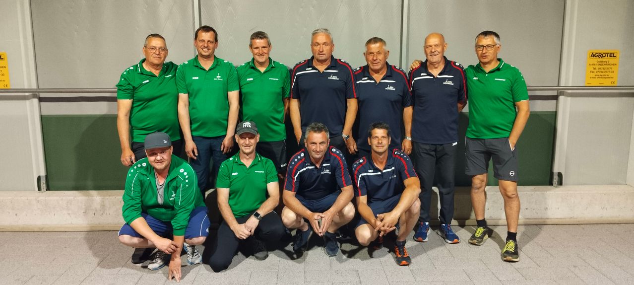 Eine Gruppe von Männern in Uniformen posiert für ein Foto. Einige sind in Grün, andere in Blau und alle tragen Mützen. Sie haben Lächeln und ernste Gesichtsausdrücke.
