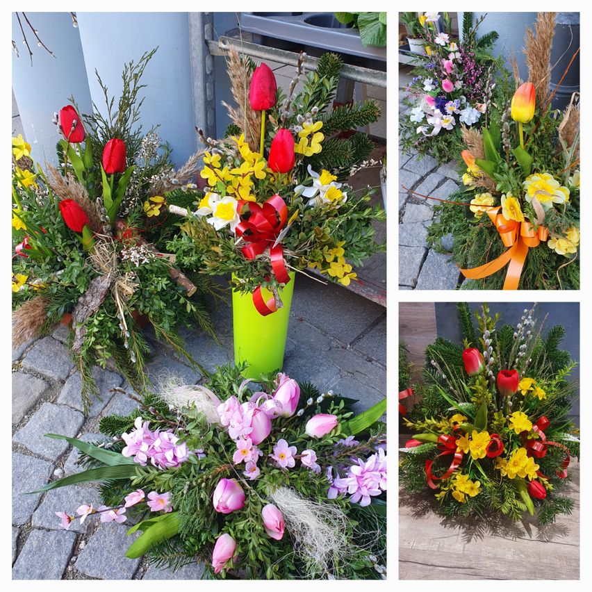 Four floral arrangements are displayed on a cobblestone surface. The first one is green with red and yellow flowers. The second is red and yellow with ribbons. The third is yellow and pink with ribbons. The last one is a mix of red, yellow, and pink flowers.