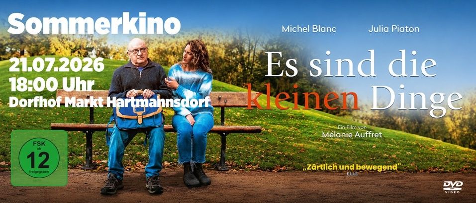 Eine Parkbank im Freien mit zwei sitzenden Personen. Ein Mann und eine Frau. Der Mann trägt eine Brille und hält eine Tasche. Die Frau trägt ein blaues Outfit. Der Hintergrund ist eine Rasenfläche mit Bäumen und einem blauen Himmel.