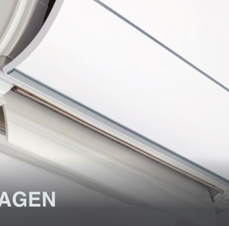 Nahaufnahme einer weißen Klimaanlage, die an einer Decke mit einer silbernen Linie montiert ist und das Wort 'MAANLAGEN' in fetten Buchstaben enthält.