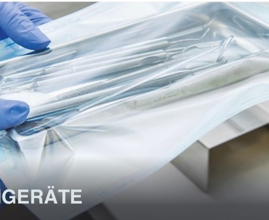 Eine Person in blauen Handschuhen hält einen durchsichtigen Plastikbehälter mit Zahninstrumenten. Der Behälter ist transparent und das Wort 'KUUMGERAATE' ist in schwarz am Boden gedruckt.