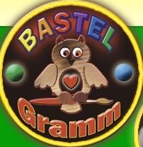 Das Bild zeigt das Logo von Bastel Gramm, das eine Eule darstellt, die einen Pinsel und eine Palette mit einem Herz in der Brust hält. Das Logo befindet sich auf einem kreisförmigen Hintergrund mit bunten Bällen drumherum.