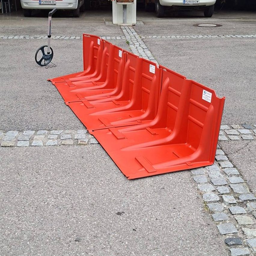 Eine Reihe roter Absperrungen steht am Straßenrand, neben einem Roller.