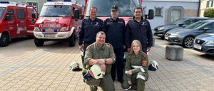 Eine Gruppe Feuerwehrleute in grünen Uniformen posiert vor einem Feuerwehrwagen mit der Aufschrift Dobřiach.