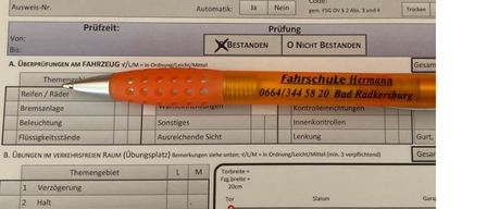 Ein Prüfprotokollblatt mit einem Stift darauf. Abschnitte umfassen 'Aktenzahl', 'Dolmetsch', 'Name', 'Prüffort' und 'Prüfstrecke'. Ein Bereich für 'Themengebiet' und 'Verzögerung' mit einem Diagramm, das eine Entfernung von 20 cm zeigt.