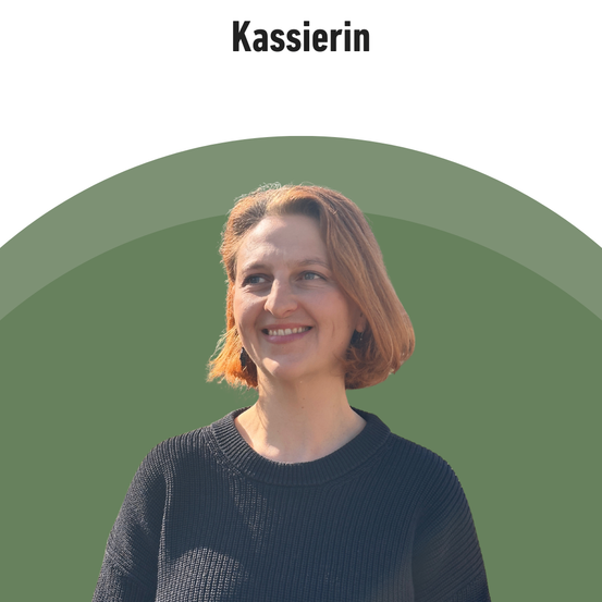 Eine lächelnde Frau mit kurzen blonden Haaren posiert für ein Foto in einem schwarzen Pullover vor grünem Hintergrund. Das Wort 'Kassierin' ist darüber angezeigt.