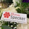 Ein Strauß weißer Blumen mit einer weißen Karte, die mit 'Blumen Specker' in Rot und Schwarz beschriftet ist. Es ist ein Fachgeschäft für Floristik, Pflanzen und Garten.
