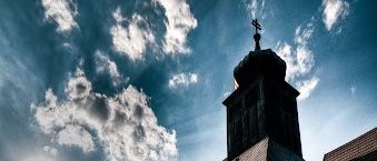 Eine Kirche mit Friedhof an einem sonnigen Tag, ein Kreuz und ein Turm in der Mitte des grünen Grases
