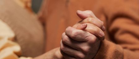 Ein Mann und eine Frau in warmer Kleidung halten Händchen. Die Frau lächelt und der Mann schaut sie an. Sie tanzen wahrscheinlich.