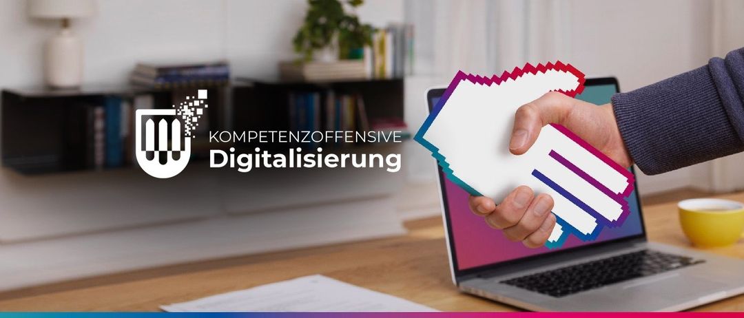 Eine Person hält ein Stück Papier mit 'Kompetenzoffensive Digitalisierung' vor einem Laptop. Dahinter steht ein Bücherregal mit Büchern und einer Topfpflanze.