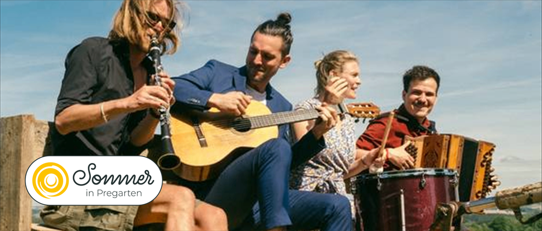 Vier Musiker spielen an einem sonnigen Tag. Ein Mann spielt Gitarre, eine Frau Schlagzeug und zwei andere spielen Klarinette und Gitarre.