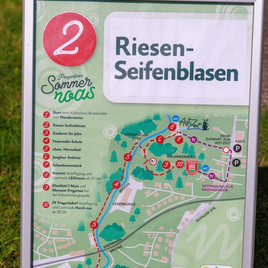 Eine Karte zeigt eine Wanderroute mit dem Titel 'Riesen-Seif enblasen'. Sie listet 10 nummerierte Stopps auf, darunter ein Kulturzentrum, ein Museum und Live-Musik-Events. Jeder Stopp hat einen roten Kreis mit einer Nummer und einer kurzen Beschreibung.