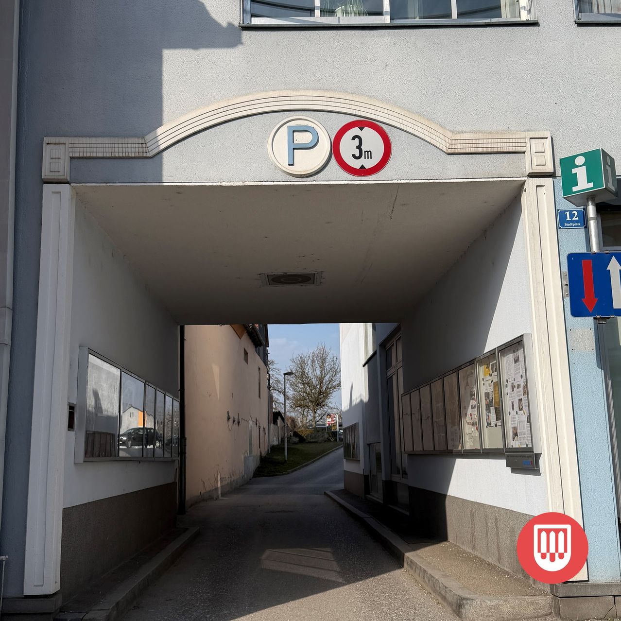 Ein Parkeingang mit einem Schild, das eine Parkhöhenbegrenzung von 3 Metern anzeigt. Der Eingang führt zu einer schmalen, gepflasterten Straße.