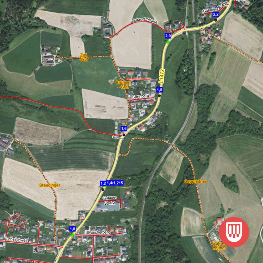 Luftbild von ländlichen Gebieten mit markierten Straßen, Entfernungen und Straßennamen, sowie einer hervorgehobenen roten Linie, die eine Route anzeigt.
