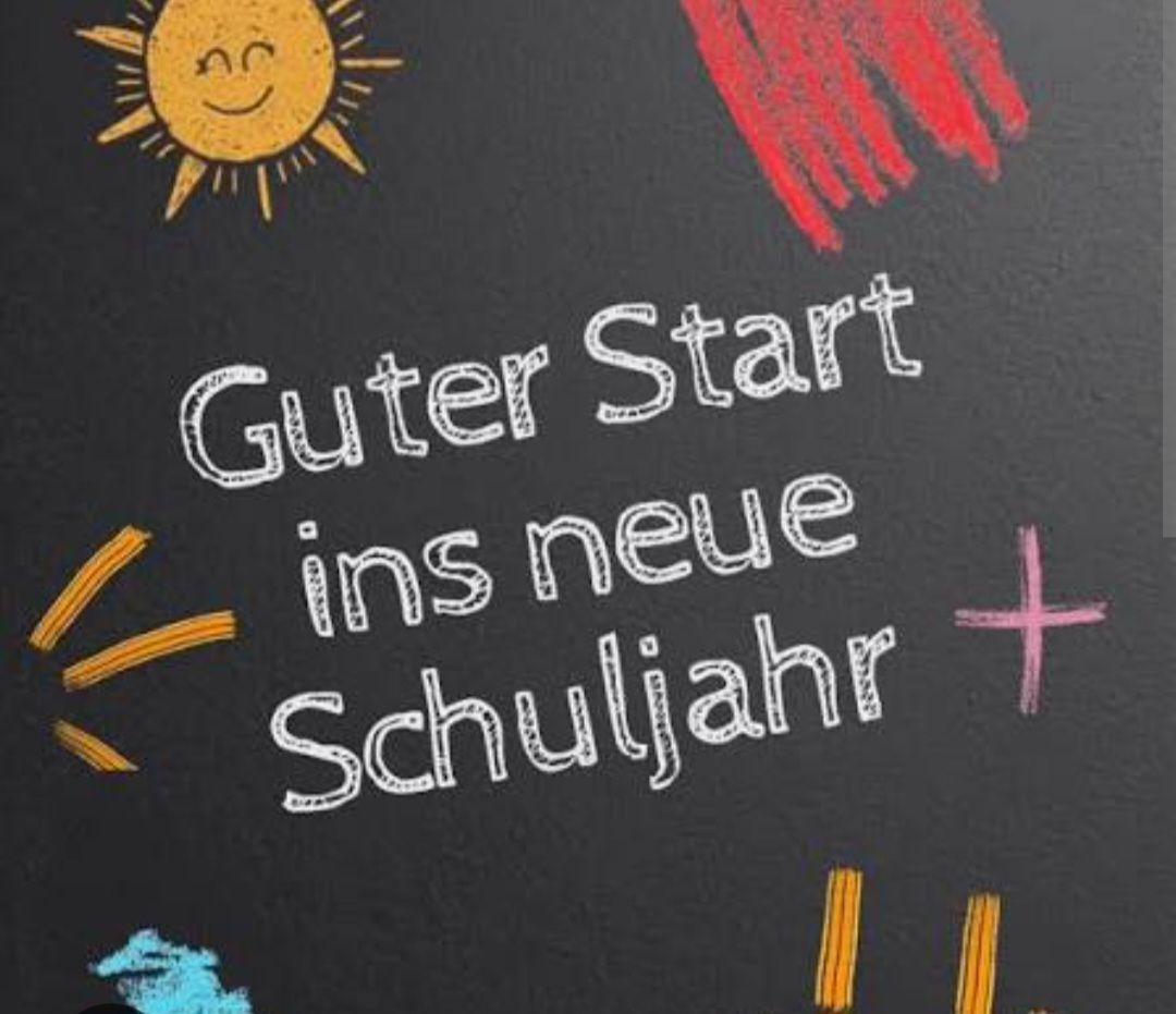 Eine Tafel mit einer fröhlichen Sonne, einer roten Hand und dem Spruch 'Guter Start ins neue Schuljahr' in weißer Kreide geschrieben.