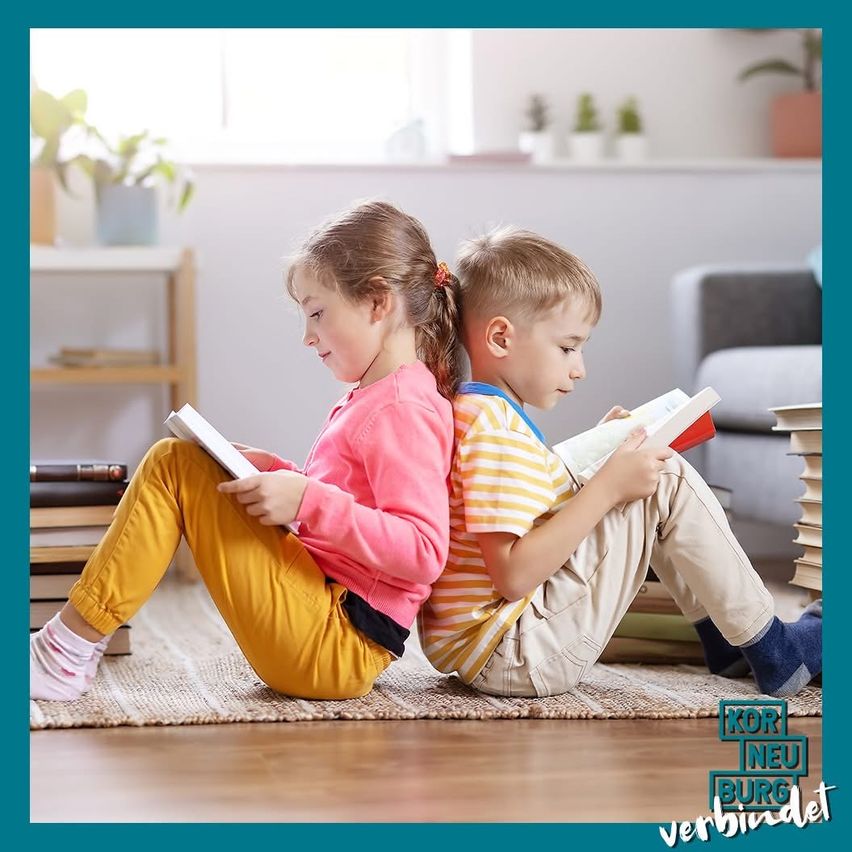 Zwei kleine Kinder sitzen auf dem Boden und lesen Bücher. Ein Mädchen trägt ein rosa Sweatshirt und gelbe Hosen. Ein Junge trägt ein gestreiftes Hemd und Khakihosen. Sie sind von Büchern und einem Teppich umgeben.