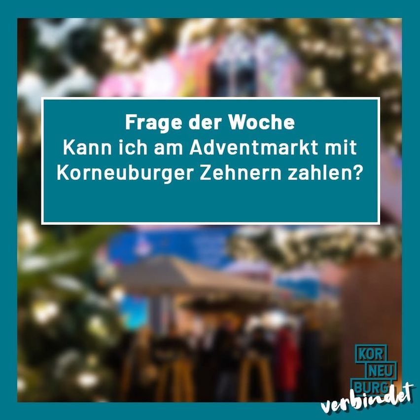 Ein blaues Schild fragt, ob man am Adventmarkt mit Korneuburger Zehnern bezahlen kann. Unscharfer Hintergrund von Menschen.