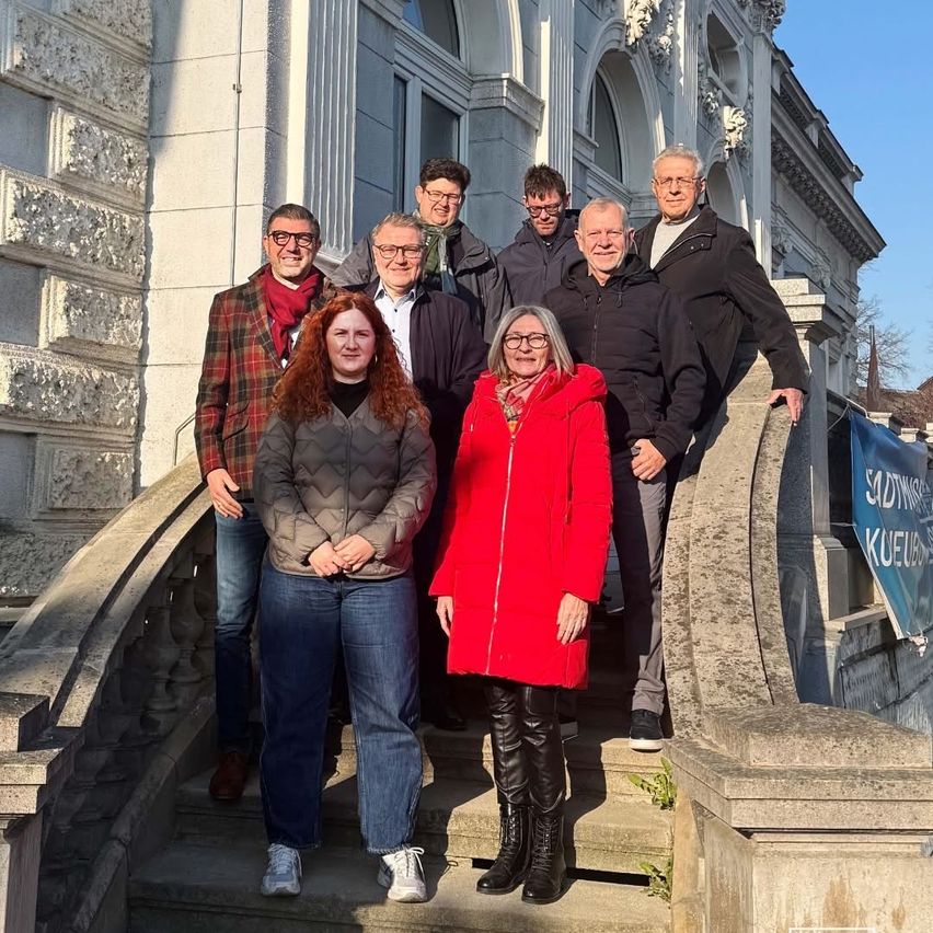 A group of people in winter clothing standing on the stairs in front of a building.