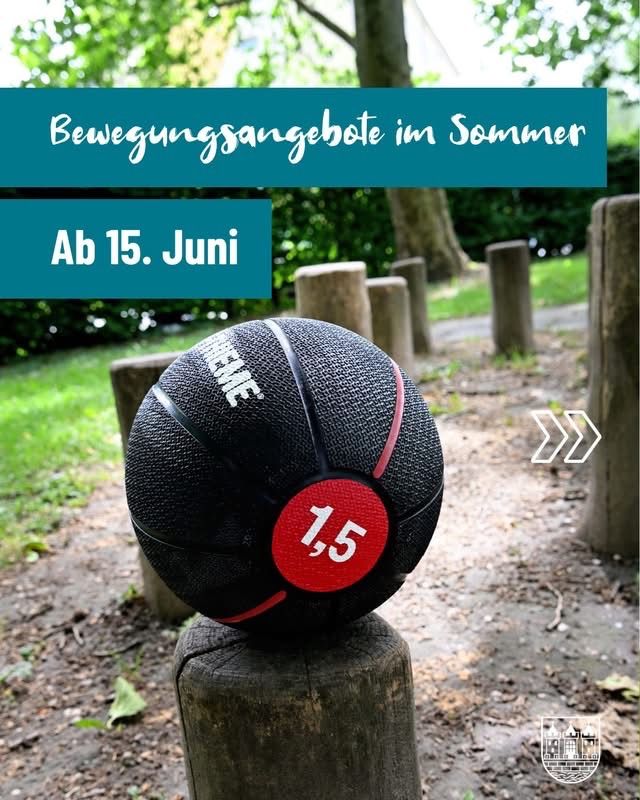 Ein schwarzer und roter Fitnessball mit der Nummer 1.5 wiegt 15 kg und steht auf einem Holzpfosten im Park. Textüberlagerung lautet 'Bewegungsangebote im Sommer' und 'Ab 15. Juni'.