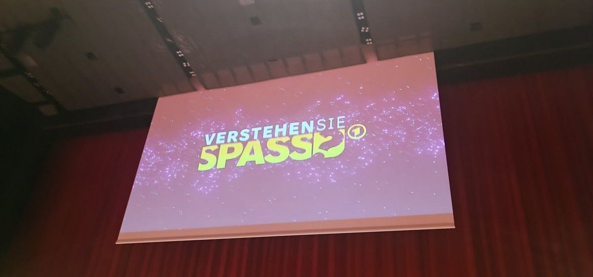 Bild enthält, People, Person, Electronics, Screen, Crowd, Cinema, Business Card, Audience, Projection Screen, Interior Design