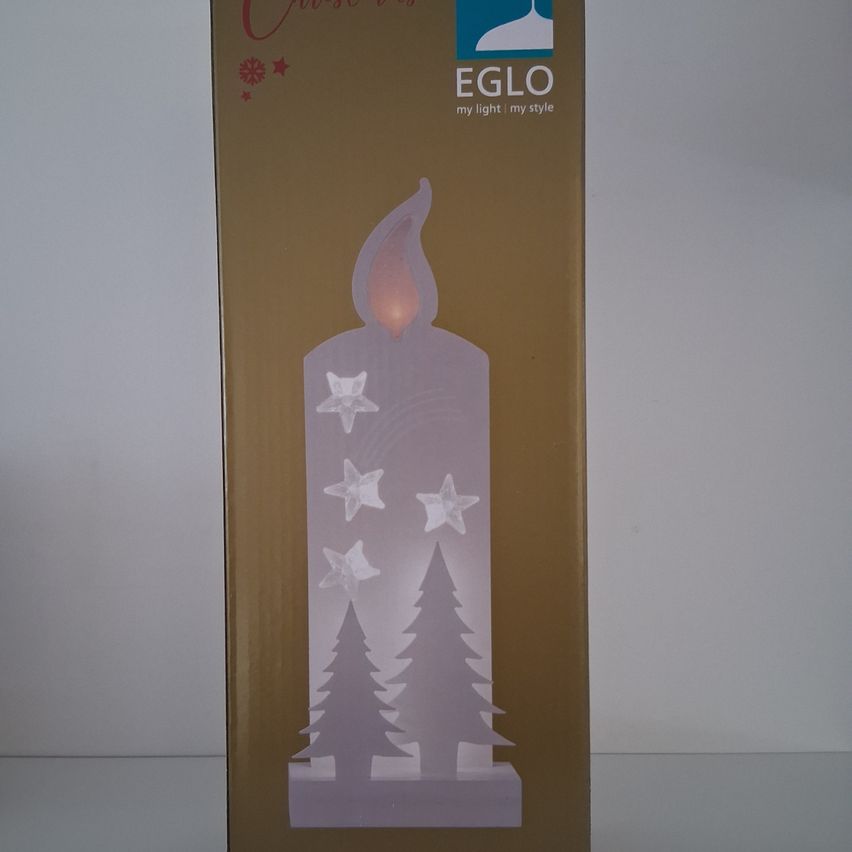 Eine Schachtel für eine Weihnachtskerze mit einer leuchtenden Kerze und Sternen und Bäumen darauf, gebrandet Eglo.
