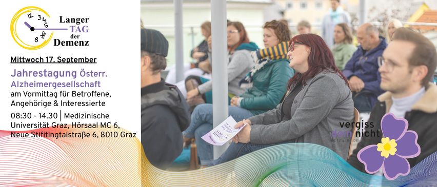 Eine Gruppe von Menschen sitzt in einem Wartebereich. Eine Frau in einer grauen Jacke liest ein Papier, während ein Mann mit Hut zusieht.