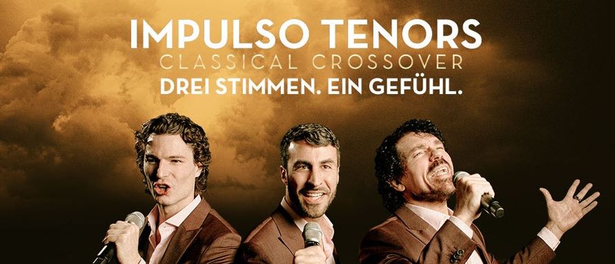 Drei Männer in braunen Anzügen singen in Mikrofone mit einem dramatischen Bühnenhintergrund. Der Text 'DREI STIMMEN. EIN GEFÜHL.' ist oben angezeigt.