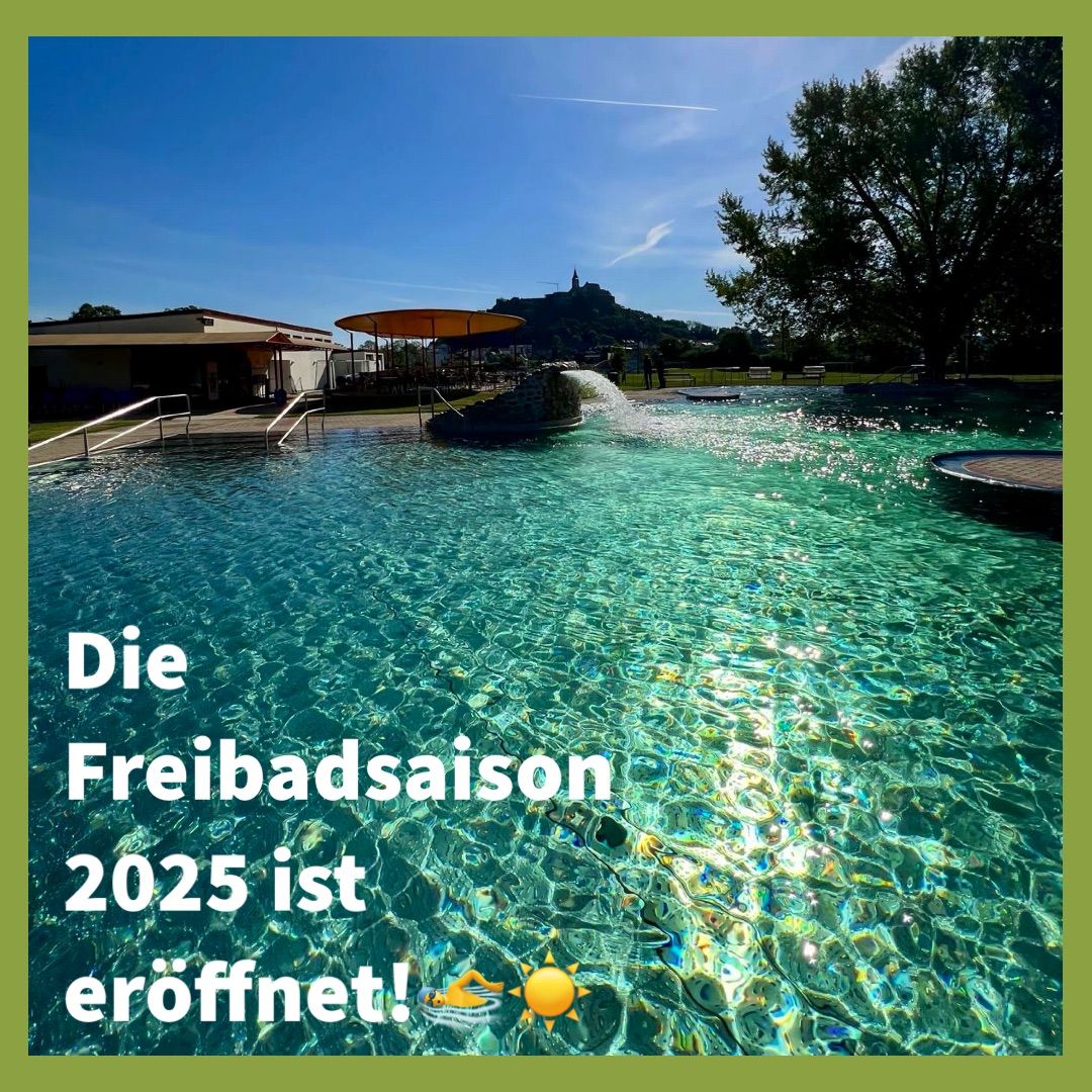 Ein Freibad mit klarem Wasser und einer Fontäne in der Mitte. Der Text auf dem Bild lautet 'Die Freibadsaison 2025 ist eroffnet!' mit einer Sonne und einer Person, die im Wasser schwimmt.