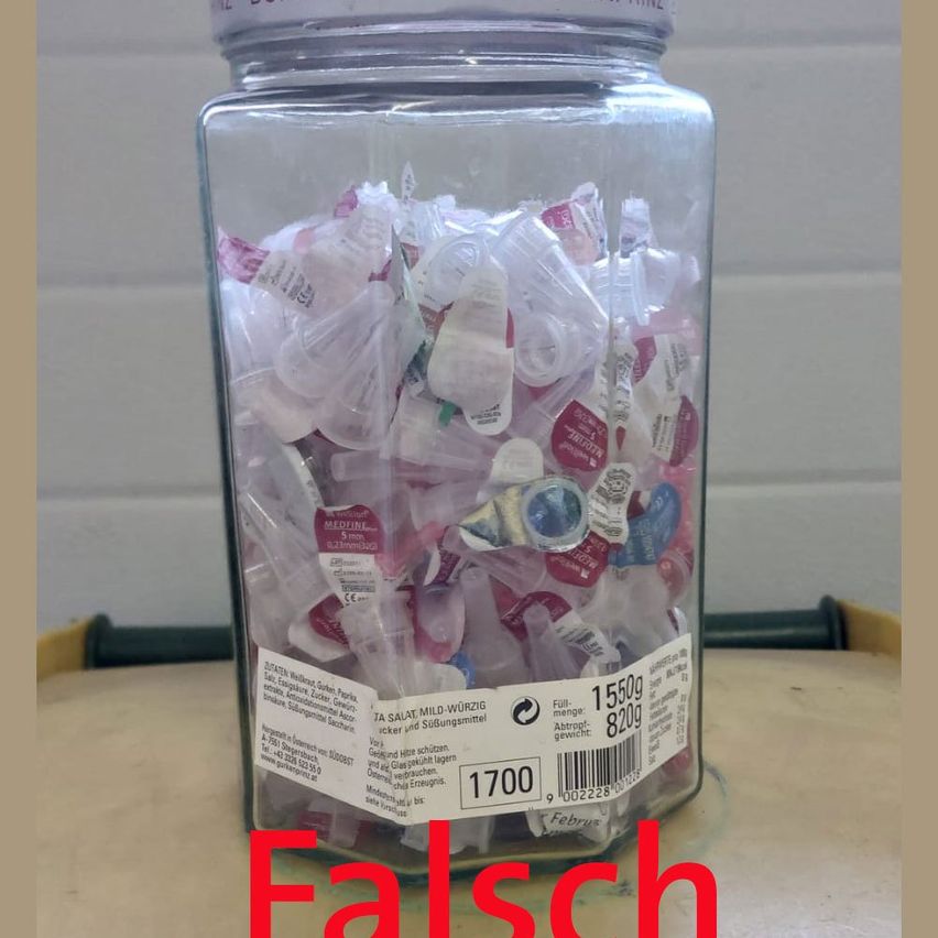 Ein Glasglas mit kleinen Packungen von Medikamenten, beschriftet mit 'Ta Salat Mild-Würzig', zeigt Menge, Gewicht und einen Barcode. Das Glas steht auf einem Holztisch.