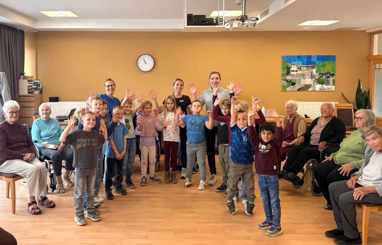 Eine Gruppe von Kindern und Erwachsenen posiert für ein Foto in einem Raum mit Holzböden.