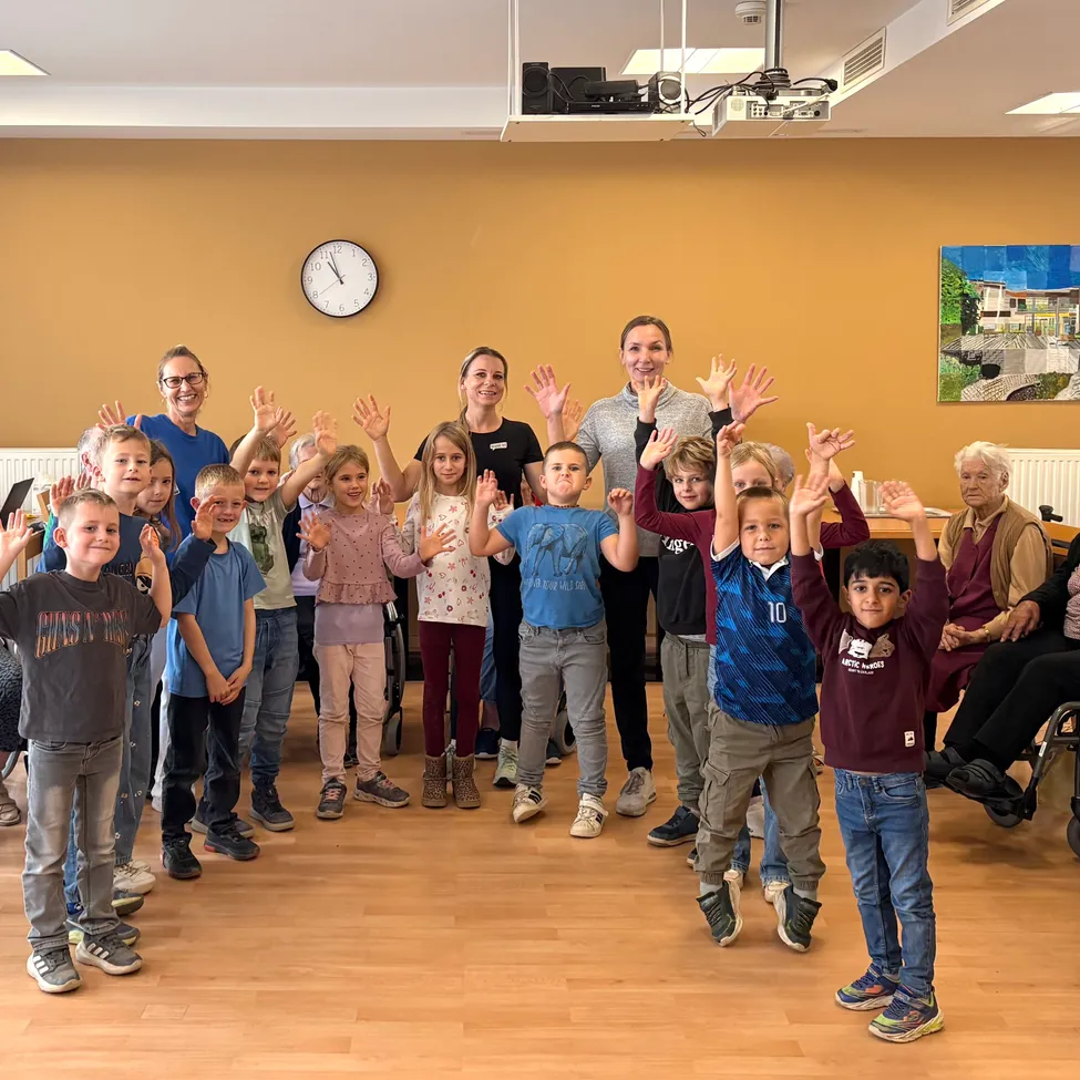 Eine Gruppe von Kindern und Erwachsenen posiert für ein Foto in einem Raum mit Holzböden.