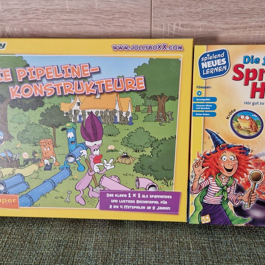 Two educational board games, one titled 'Pipeline-Konstrukteurs' and the other 'Die Spiel', displayed on a wooden surface.