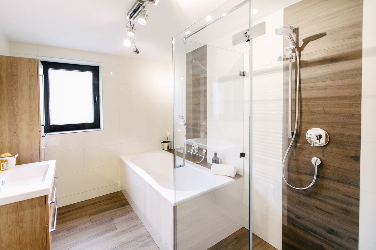Badezimmer mit Badewanne, Dusche, Waschbecken und Holzdekor