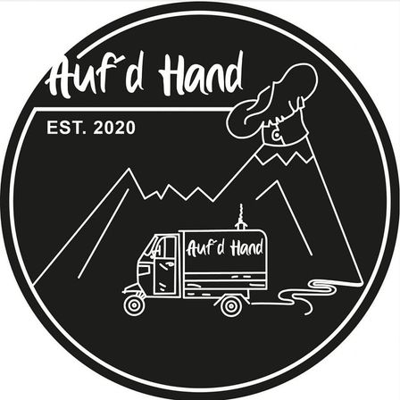 Schwarz-Weiß-Logo für Auf d Hand, gegründet 2020. Es zeigt einen Berg, einen Koch und einen Food-Truck. Der Koch hält eine Schöpfkelle und der Food-Truck trägt die Aufschrift Auf d Hand.