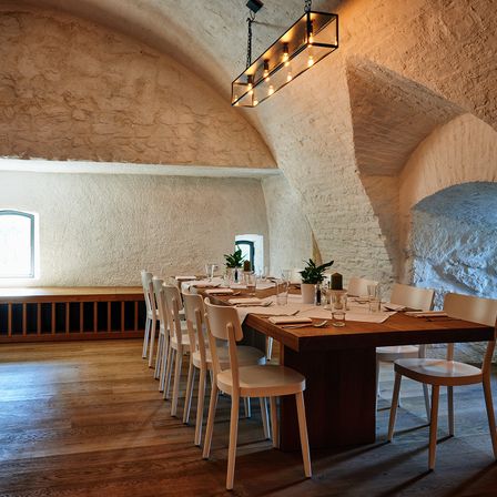 Ein großer Esszimmer mit Holzboden, weißen Wänden und einem langen Holztisch, der für eine Mahlzeit gedeckt ist.