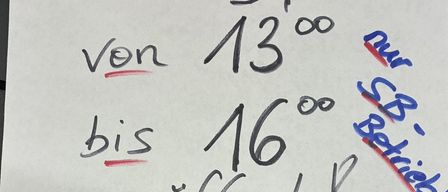 Ein weißes Papier mit einer handgeschriebenen Nachricht in schwarzer und roter Tinte. Es steht 'Sonntag, 21.12.' mit 'Von 13:00 bis 16:00 geöffnet?' und '-21%'. Es gibt eine rote Linie unter 'Sonntag' und eine rote Linie unter '21'.