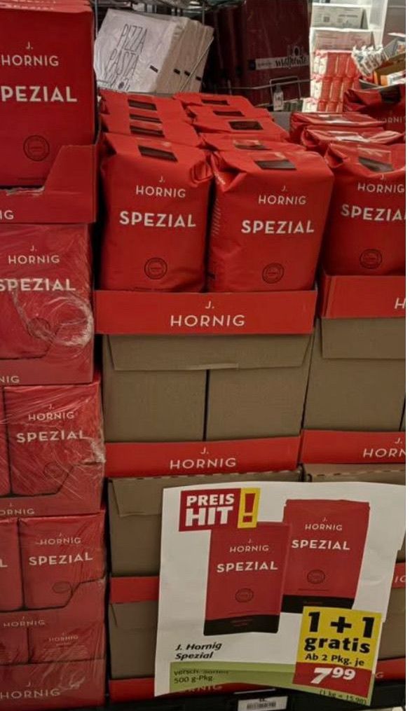 Ein Stapel roter Boxen mit der Aufschrift 'Hornig Spezial'. Die Boxen sind in einem Geschäft angeordnet, mit einem weißen Etikett 'Preis Hit' unten rechts.
